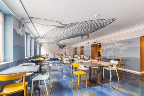 een restaurant met tafels en stoelen en een walvis geschilderd op het plafond bij Hotel Britannia in Genua