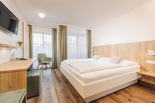 a bedroom with a large white bed and a desk at Hotel Garni Gästehaus am Mühlbach in Ottobeuren