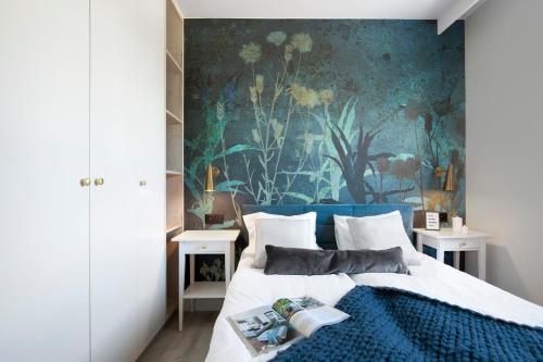 a bedroom with a bed with a painting on the wall at Elite Apartments Brzeźno Premium in Gdańsk