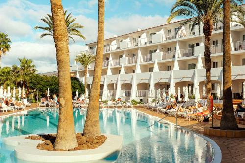 een zwembad met palmbomen en een hotel bij Sunprime Atlantic View Suite & Spa in Playa del Inglés