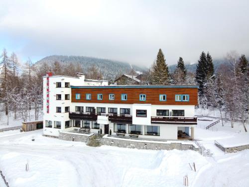un gran edificio en la nieve con suelo cubierto de nieve en Hotel Berghof, en Seefeld in Tirol