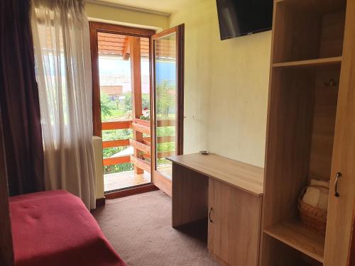 a bedroom with a desk and a door to a balcony at PENSIUNEA LEIA Transfăgărășan in Cîrţişoara