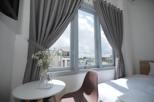 a room with a window with a table and a vase with flowers at M Hotel Đà Lạt in Da Lat