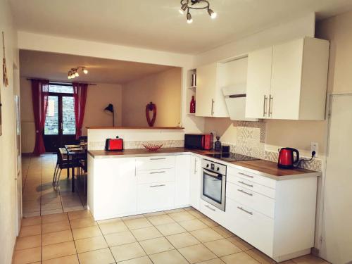 a kitchen with white cabinets and a dining room at Gîte des 3 vallées in Baume-les-Messieurs