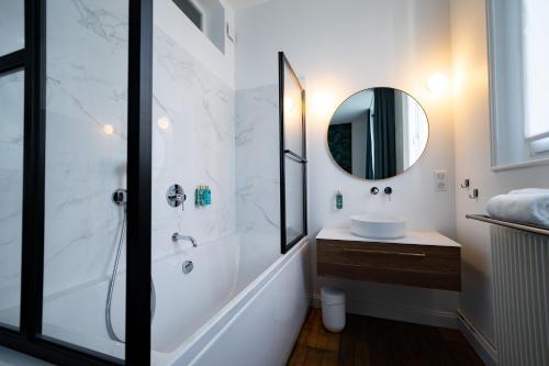 ein Bad mit einer Dusche, einem Waschbecken und einem Spiegel in der Unterkunft Centre ville - Appartement 3 chambres & Terrasse - La Clé des Sacres in Reims