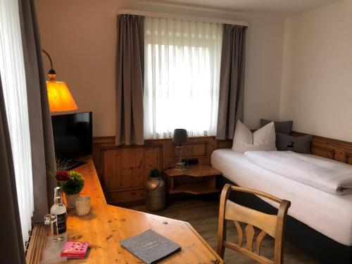 a hotel room with a bed and a table and a television at Mäsers Allgäuherz in Wiggensbach