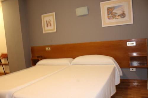 2 camas en una habitación de hotel con sábanas blancas en Hotel Fuente La Plata, en Oviedo