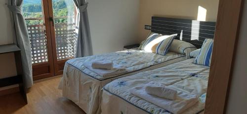 - une chambre avec 2 lits et une grande fenêtre dans l'établissement Casa Rural FULGUERA, à El Espino