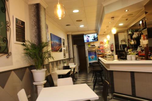 ein Restaurant mit weißen Tischen und Stühlen und eine Bar in der Unterkunft Hotel Fuente La Plata in Oviedo
