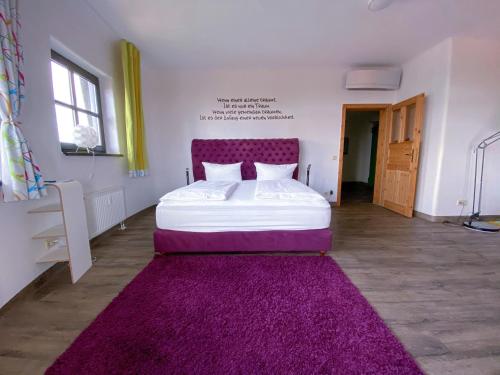 a bedroom with a bed with a purple headboard and a purple rug at apartHOTEL Magdeburg in Magdeburg