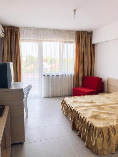 a bedroom with a bed and a red chair at Villa Anastasia in Costinesti