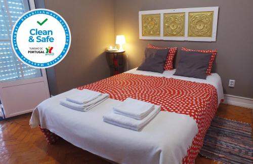 a bedroom with a red and white bed with towels on it at Alvalade II Airport Guest House in Lisbon