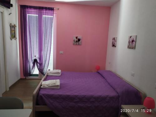 a bedroom with a purple bed and a window at La vie est belle in Finale Ligure
