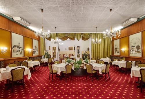 un comedor con mesas y sillas blancas y lámparas de araña en Hotel Austria - Wien en Viena