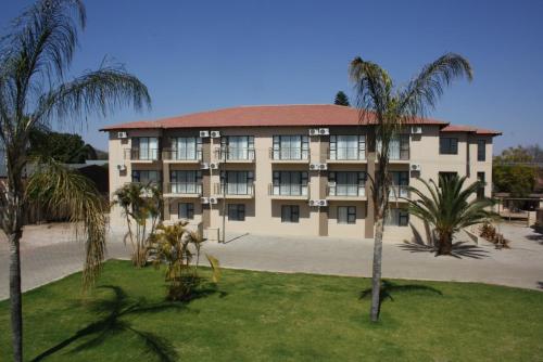 a large building with palm trees in front of it at Oasis Hotel in Mokopane