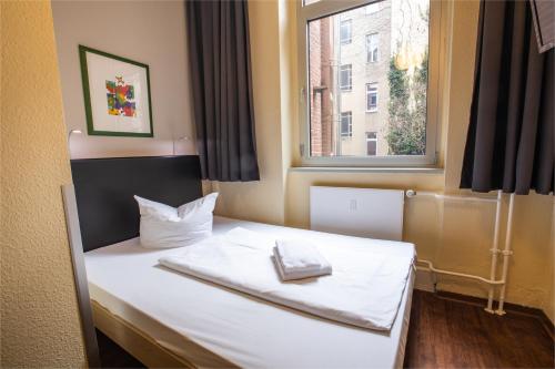 a bedroom with a white bed with a window at acama Hotel & Hostel Kreuzberg in Berlin
