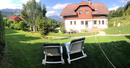 two chairs sitting in the grass in front of a house at Ferienhaus Schaller am Galsterberg in Pruggern