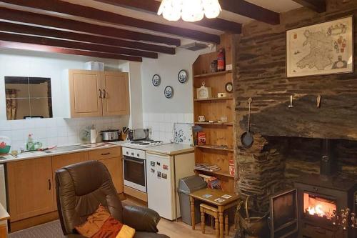 a kitchen with a stove and a stone fireplace at Self Catering Cottage in Talsarnau