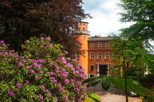 an orange building with pink flowers in front of it at Pałac Paulinum in Jelenia Góra