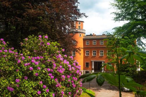 um edifício laranja com flores cor-de-rosa à frente em Pałac Paulinum em Jelenia Góra