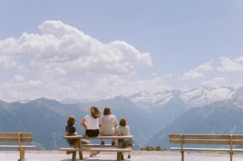 a group of people sitting on a bench looking at mountains at Hotel Blü Gastein in Bad Hofgastein