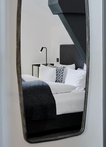 a mirror reflecting a bed with white sheets and pillows at Landhaus Flottbek Boutique Hotel in Hamburg