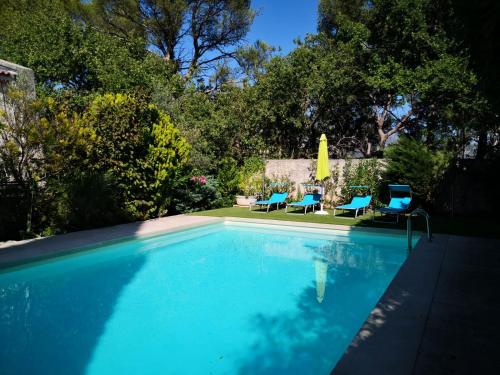 a swimming pool with two chairs and a umbrella at Lou Pauseto in Aubagne