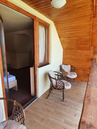 a balcony with chairs and a table in a cabin at PENSIUNEA LEIA Transfăgărășan in Cîrţişoara