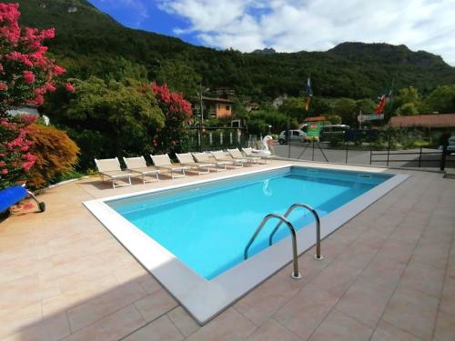 a swimming pool with chairs and a mountain in the background at Villaggio Turistico Il Lago Dorato in Carlazzo