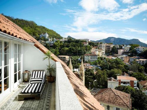 a balcony with two chairs and a view of a city at Santa Teresa Hotel Rio de Janeiro - MGallery Collection in Rio de Janeiro
