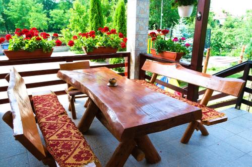 une table et des chaises en bois sur une terrasse fleurie dans l'établissement Arnota, à Costeşti