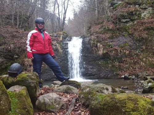 a man standing on rocks in front of a waterfall at Complex Turistic Caprioara in Baia Mare
