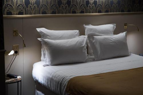 a bedroom with a bed with white sheets and pillows at Hôtel Léna in Paris