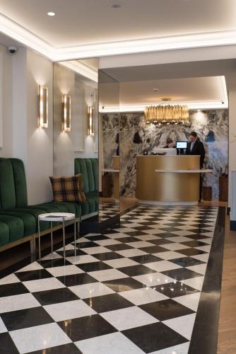 a lobby with green chairs and a reception desk at Hôtel Léna in Paris