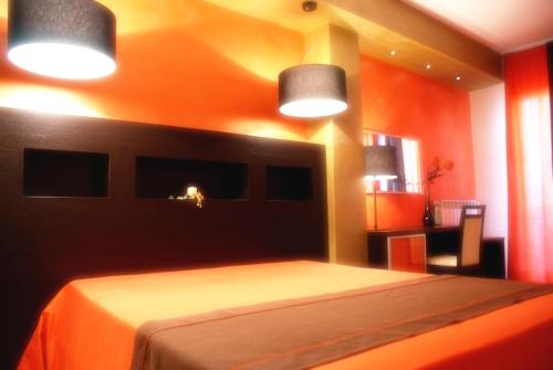a bedroom with a bed with orange walls and two lights at B&B Alixia in Alezio