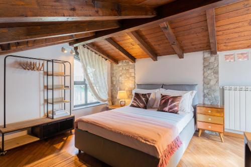 sypialnia z łóżkiem w pokoju z drewnianym sufitem w obiekcie Villa Castello with jacuzzi & priceless view by Rent All Como w mieście Argegno