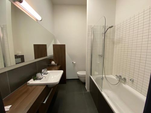 een badkamer met een wastafel, een bad en een toilet bij Hotel De Boskar Peer in Peer