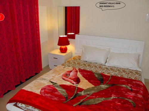 a bedroom with a bed with a red blanket and a red lamp at JANNAT VILLA in Lonavala