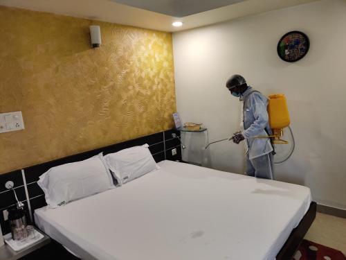 a man in a room disinfecting a bed with a hose at Hotel Shree Vatika in Bhopal