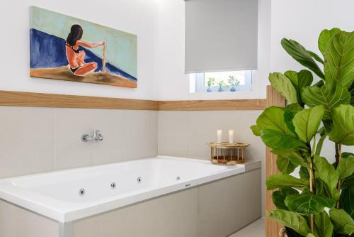 ein Badezimmer mit einer Badewanne und ein Gemälde einer Frau in der Unterkunft Balance Hotel in Chania
