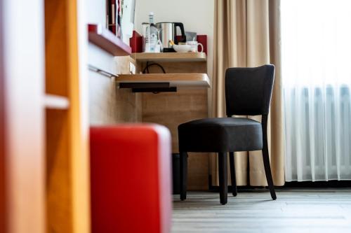 a room with a chair and a desk and a table at INSIDE Nordhorn by Hackmann in Nordhorn