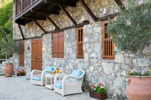 a patio with wicker chairs and a stone building at Casale Panayiotis in Kalopanayiotis