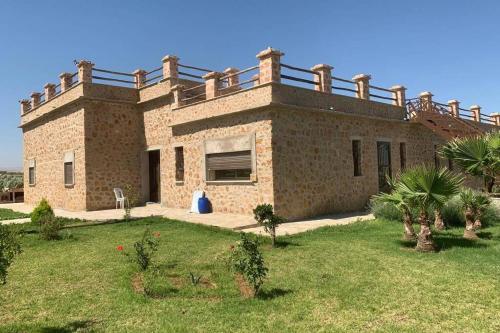 a large brick house with a garden in front of it at Villa ChezMoi in Oulad Tayeb