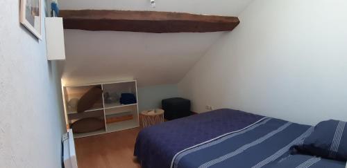 een slaapkamer met een blauw bed en een witte muur bij Le gîte de l'atelier in Lailly-en-Val
