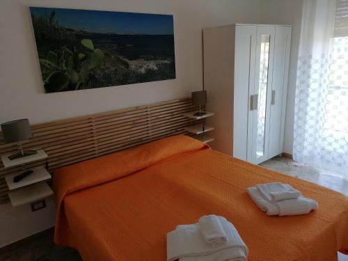 una camera da letto con un letto arancione con due asciugamani di A Ficurinia a Siracusa