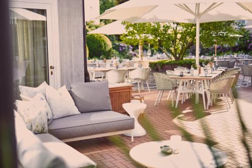 a patio with a couch and tables and chairs at VILA VITA Rosenpark in Marburg an der Lahn