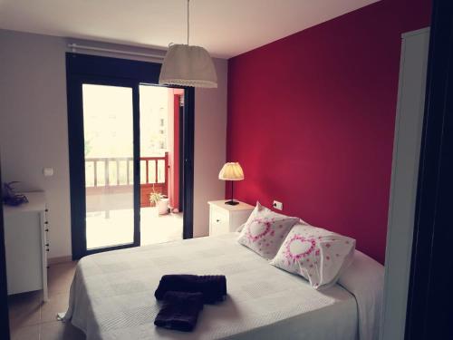 1 dormitorio con cama blanca y pared roja en Apartamento de lujo en Residencial El Mocan, en Palm-mar