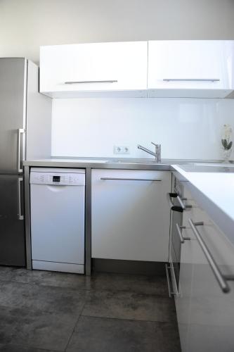 eine weiße Küche mit einer Spüle und einem Geschirrspüler in der Unterkunft Ferienzimmer Ellisee, kontaktloser Check-in in Friedrichshafen