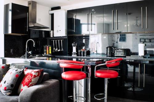 una cocina con taburetes rojos frente a un mostrador de cocina en The Arches Apartments en Barrow in Furness