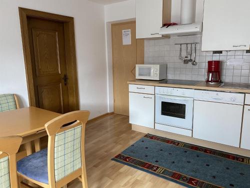 a kitchen with white appliances and a table with chairs at Harpfner in Finkenberg